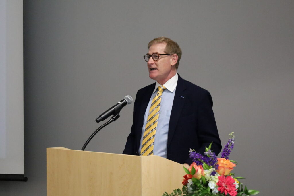 Plastic surgeon Steven Buchman delivers lecture at podium with microphone and flowers