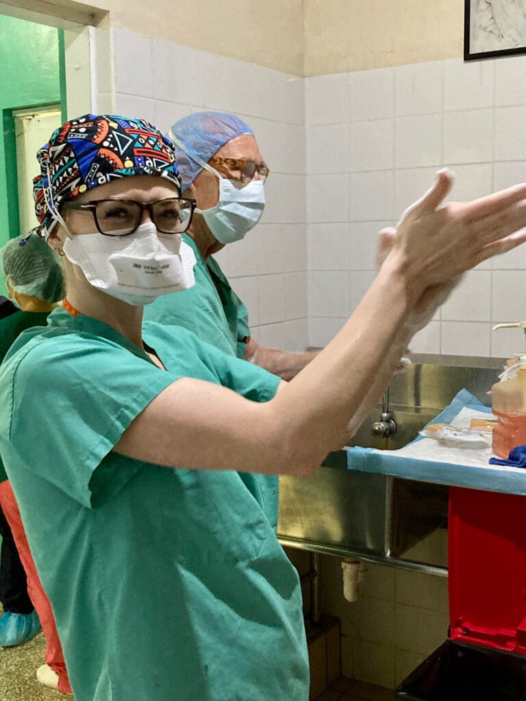 Surgeon Hailey Shepherd in scrubs and cap preparing for surgery in El Salvador OR