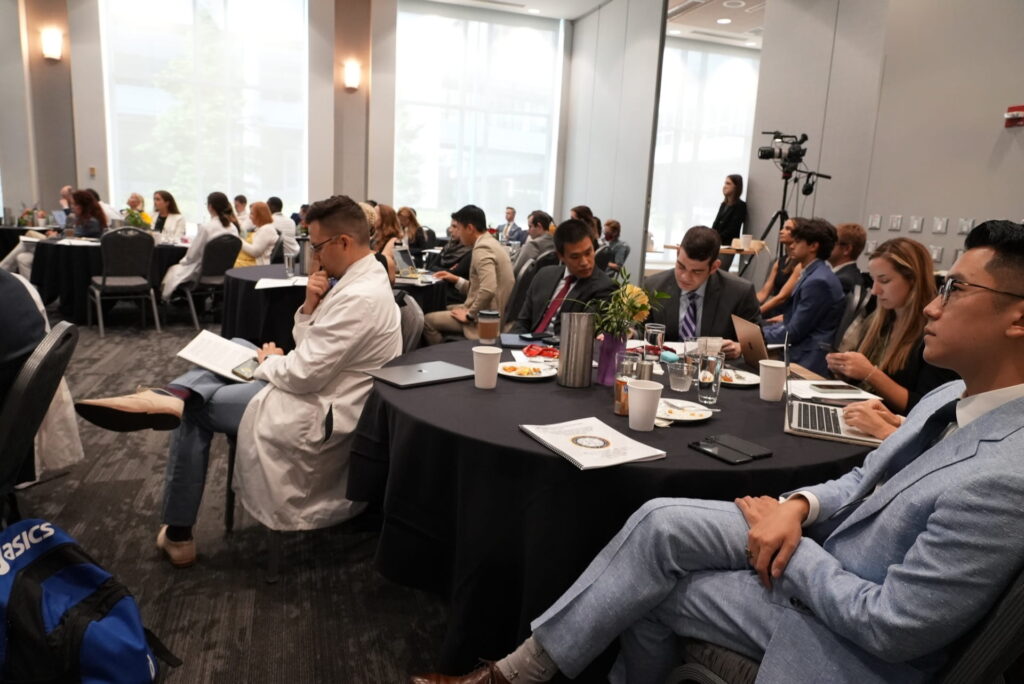 Audience listens to presentations in conference room during visiting professorship at medical school