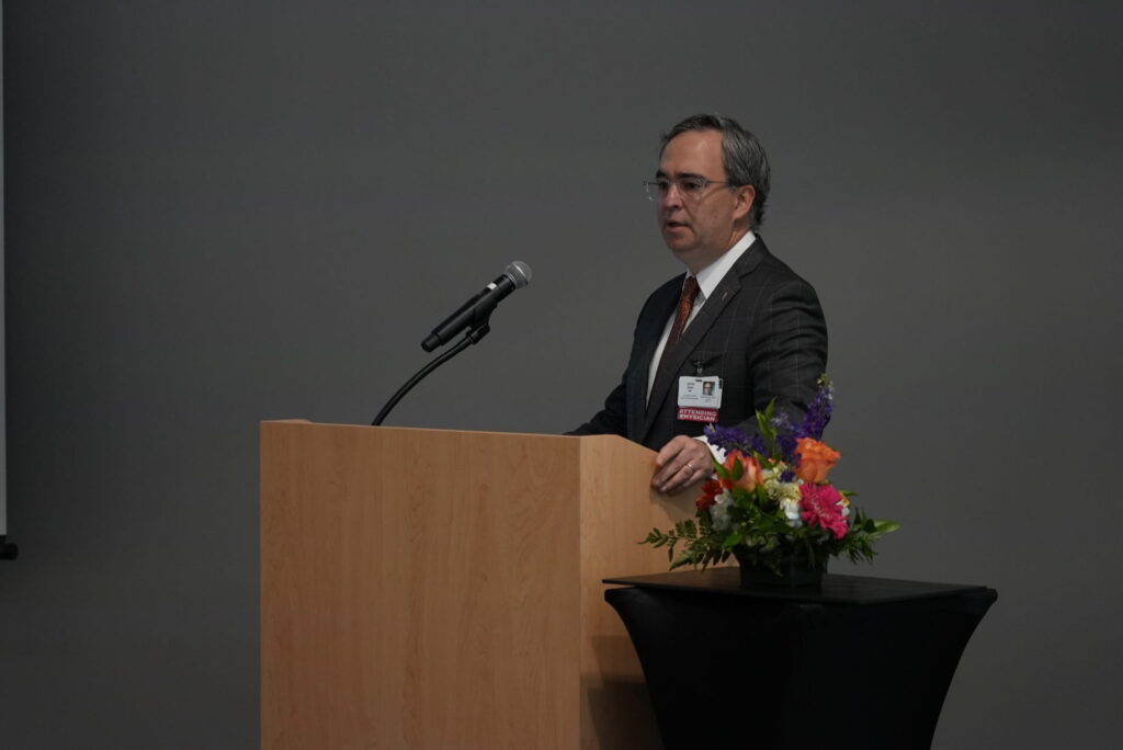 Plastic surgery chief Justin Sacks at podium with microphone and flowers