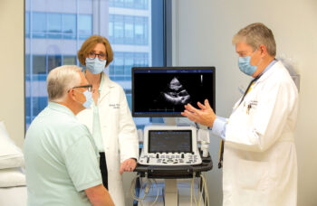 Doctors and patient in office looking at image of scan on monitor