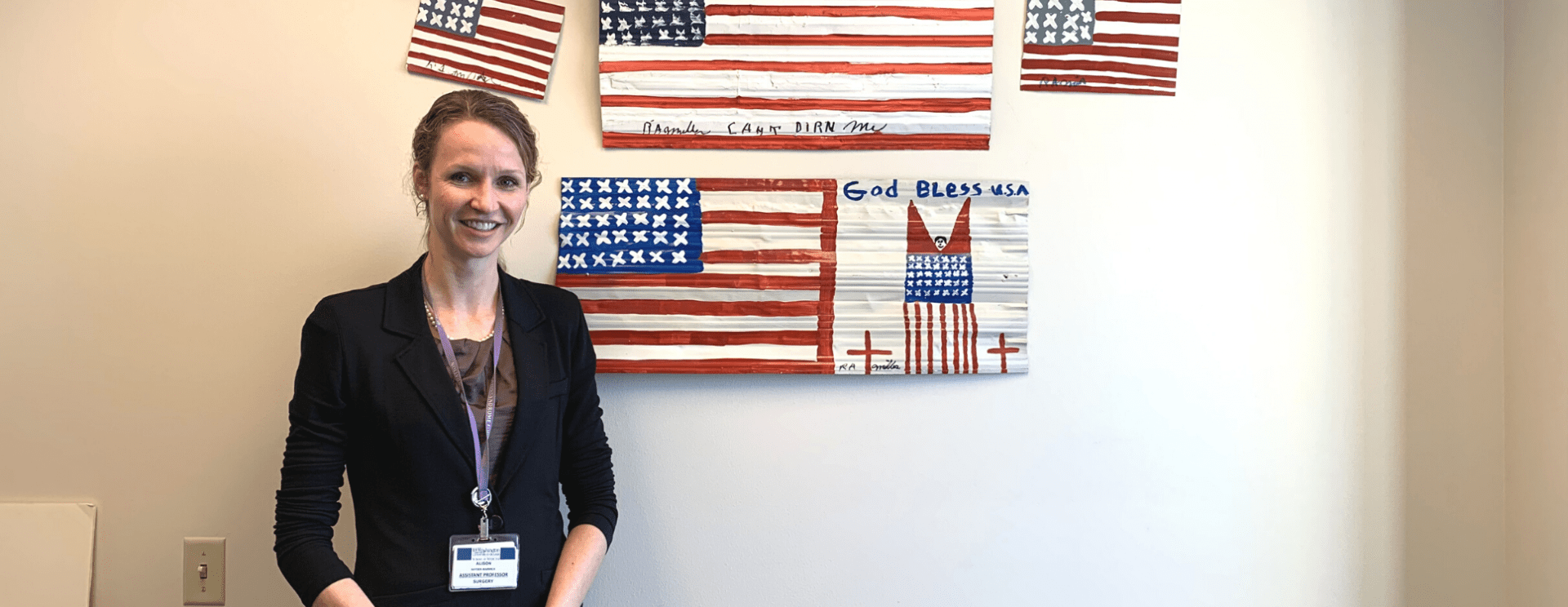 Alison Snyder-Warwick, MD, smiles in front of patriotic art in the Plastic and Reconstructive Surgery Department. 