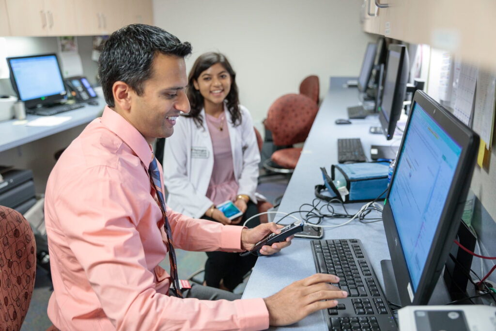 Kamlesh Patel and medical student sitting at computers