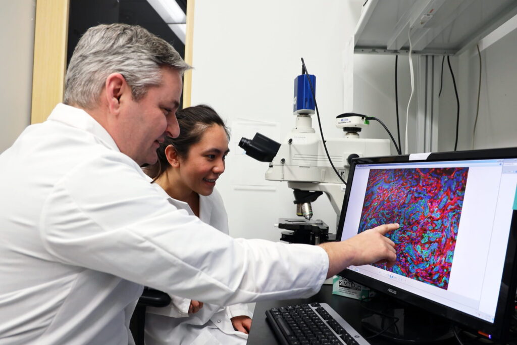 Doctor DeNardo and medical student examining microscope image in lab