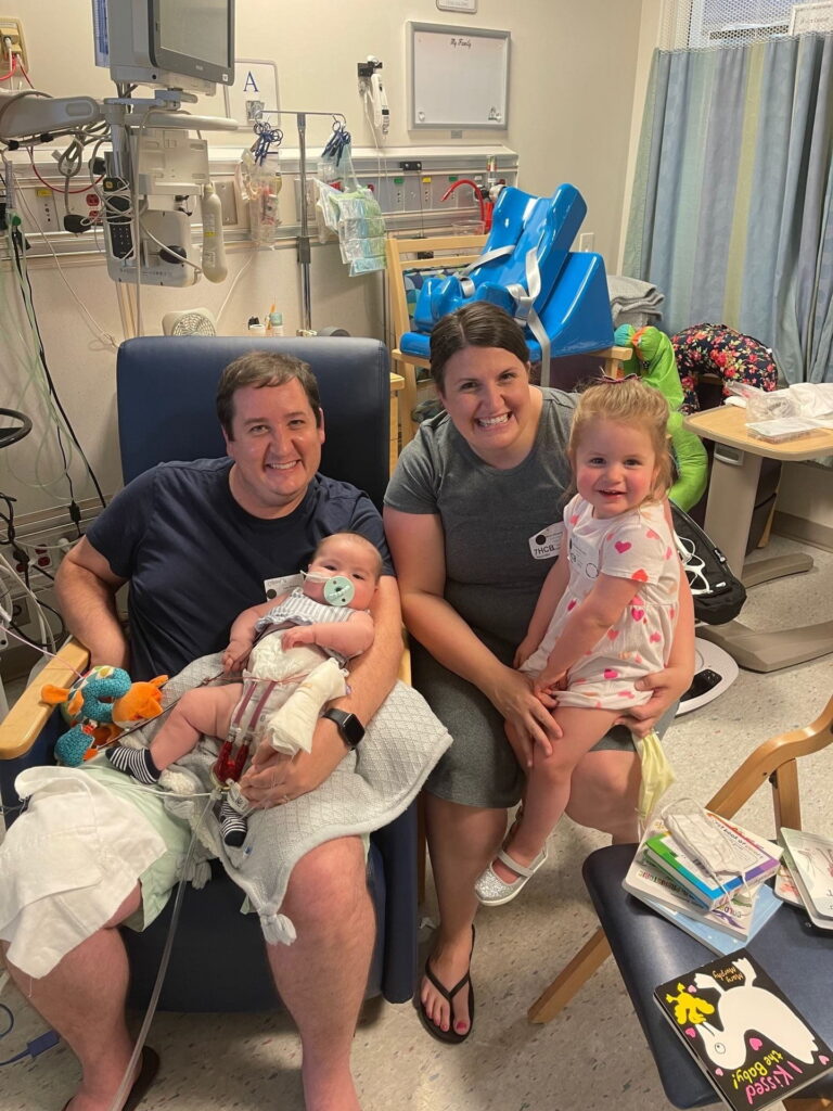 Mother and father with two young daughters in Children's Hospital room with medical equipment