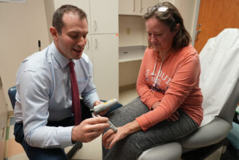 Dr. Pet listens to pulse in patient's fingers using ultrasound in clinic room